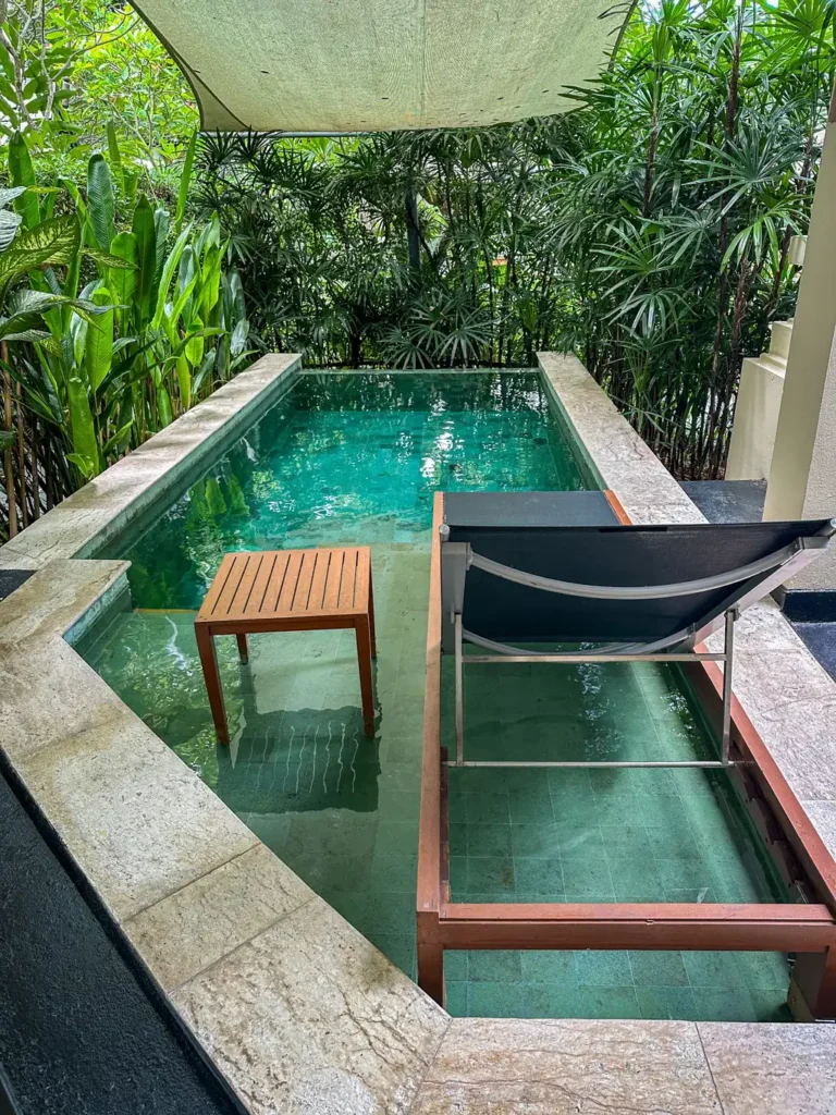 Anantara Bophut Koh Samui – Honest Family Review 2025 7 A chair and a pool with trees around it.