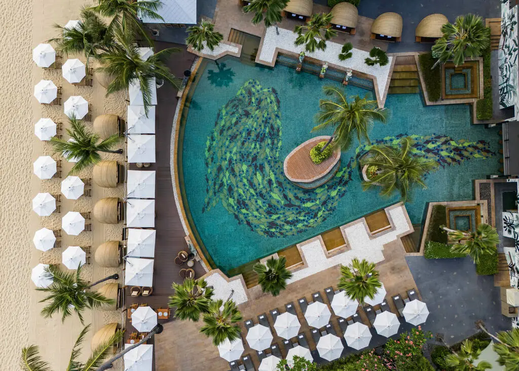 Anantara Bophut Koh Samui – Honest Family Review 2025 33 A swimming pool with palm trees and umbrellas.