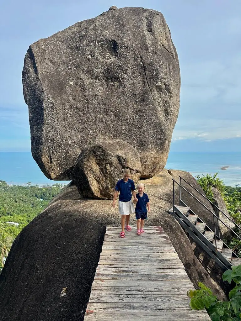 Koh Samui with Kids: 25 Super Fun Things to Do in 2025 15 Two girls standing on a wooden platform with a large rock in the background.