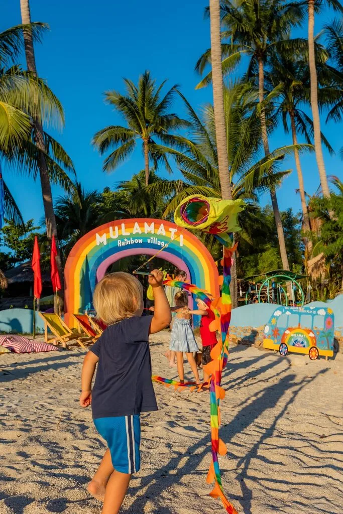 Koh Samui with Kids: 25 Super Fun Things to Do in 2025 31 A child standing on a beach with a rainbow.