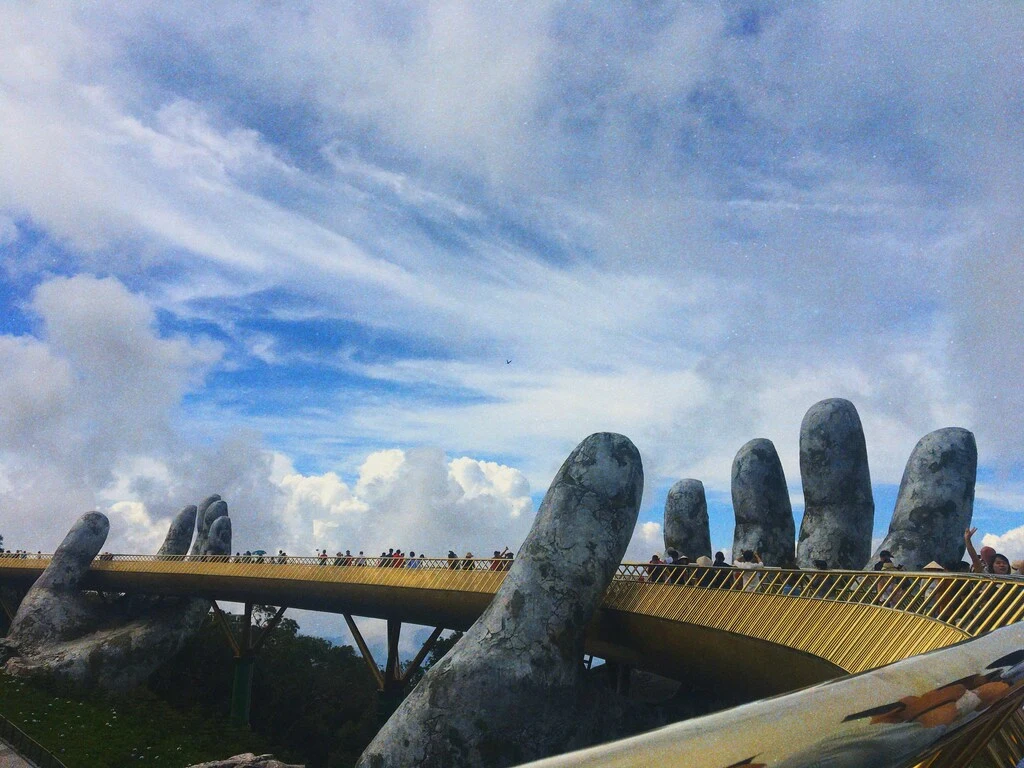 Large hand statue with people walking on it.