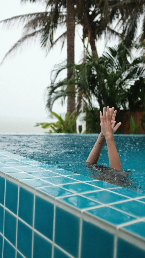 Rainy Season in Thailand – All You Need to Know 3 A person in a pool with their hands up during rainy season in Thailand.
