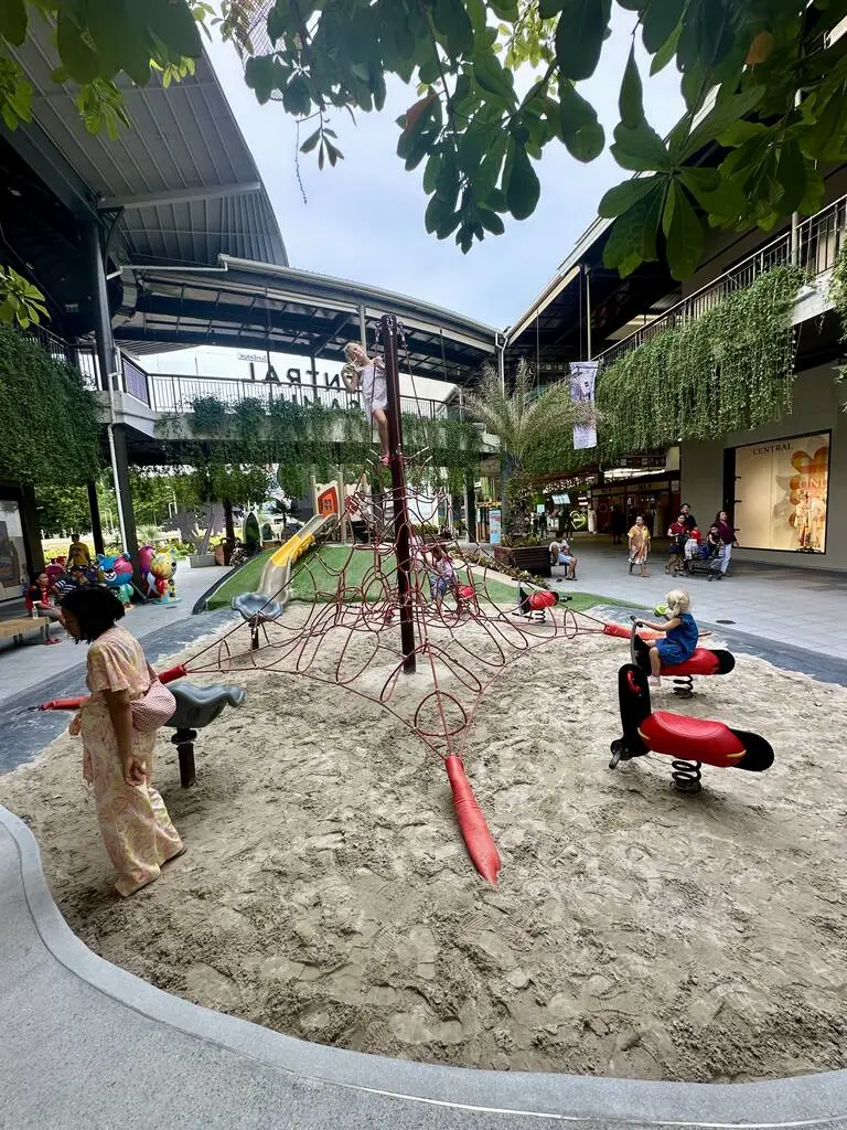 Koh Samui with Kids: 25 Super Fun Things to Do in 2025 23 A playground with a rope structure and people in the background.