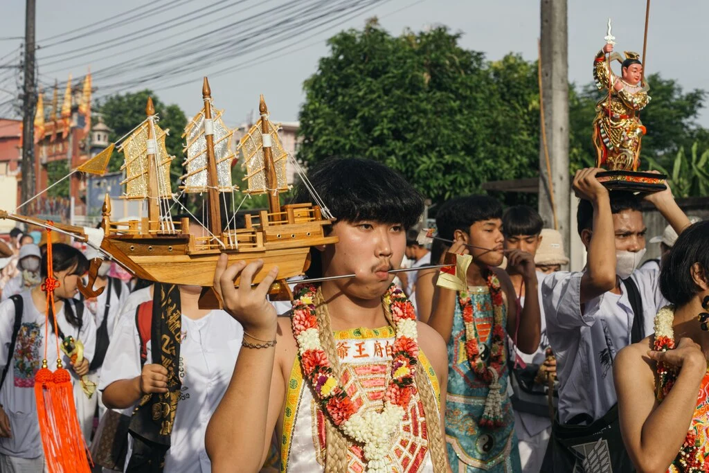 a group of people walking with a wooden boat on their head