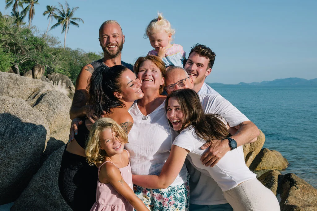 Big family having a group hug on a beach.