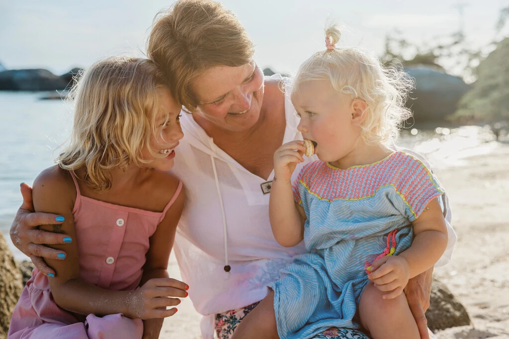 Woman with two kids sitting on a beach.