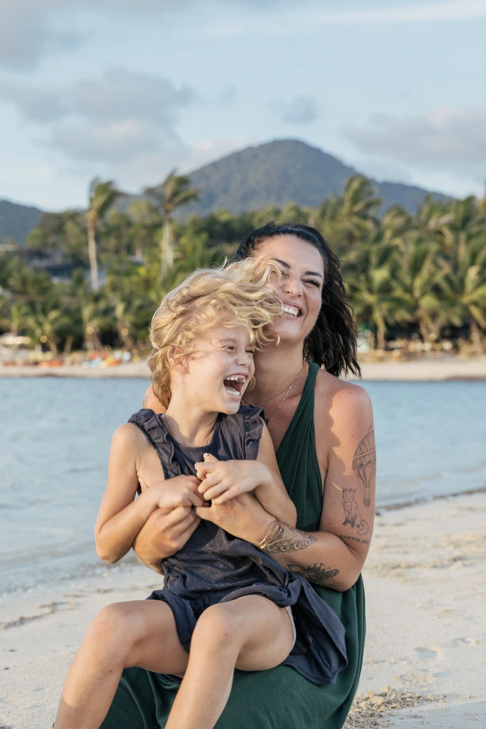 Mother and daughter laughing together on a beach.