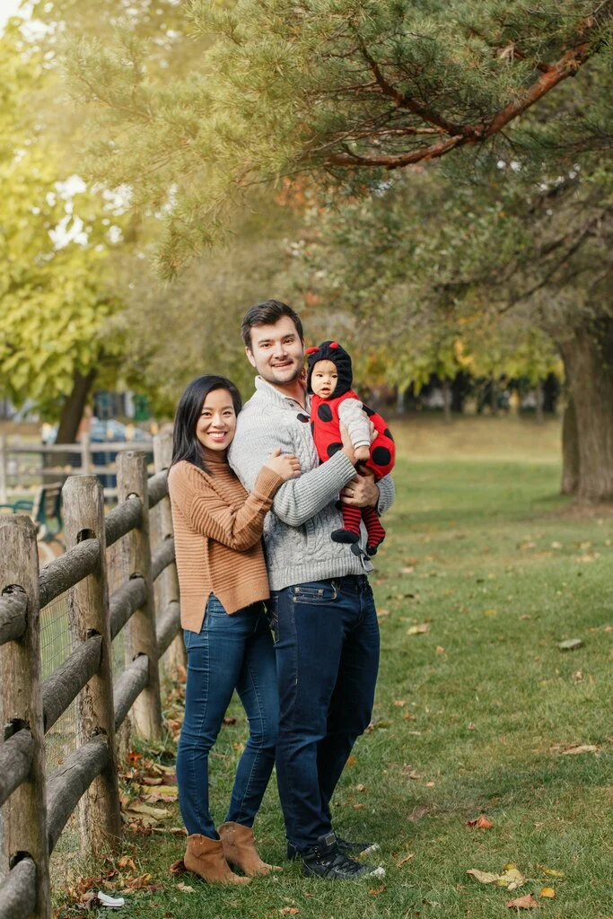 Family of three standing on a green field.