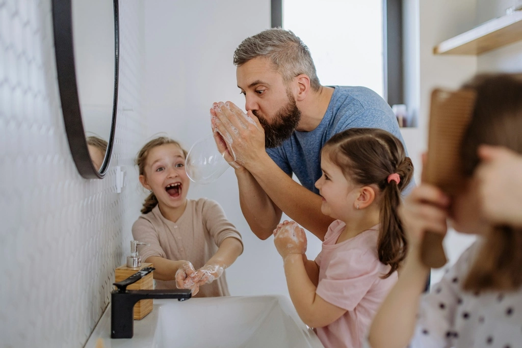 A man making fun in the bathroom with two girls.