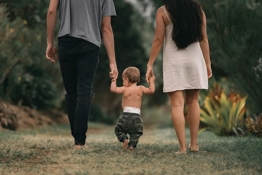 Family of three walking on gras.