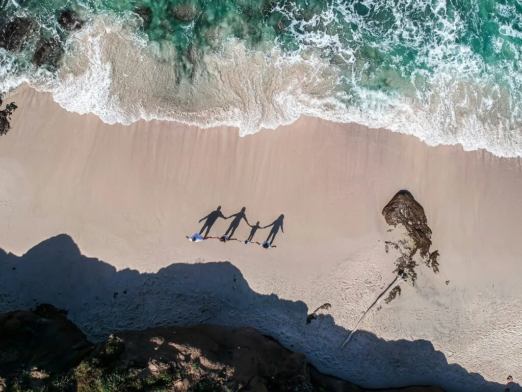 A family from above, standing on a beach.