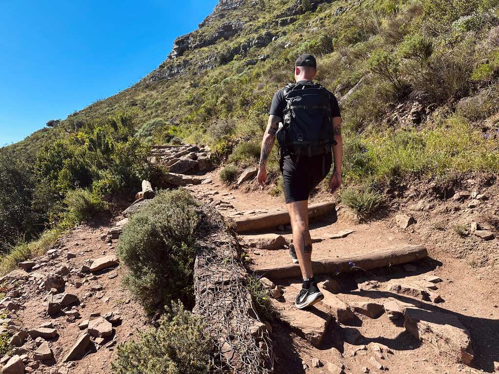 Hiker ascending rocky trail in nature.