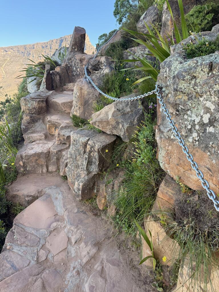 Rocky hiking trail with chain railing.