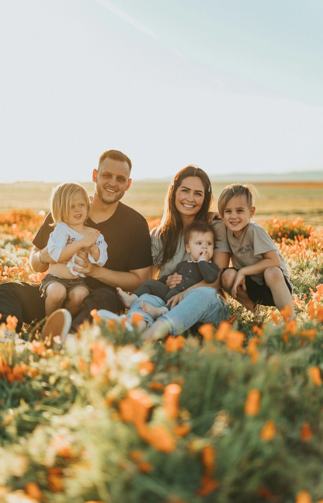 Family of five sitting in a flower field.