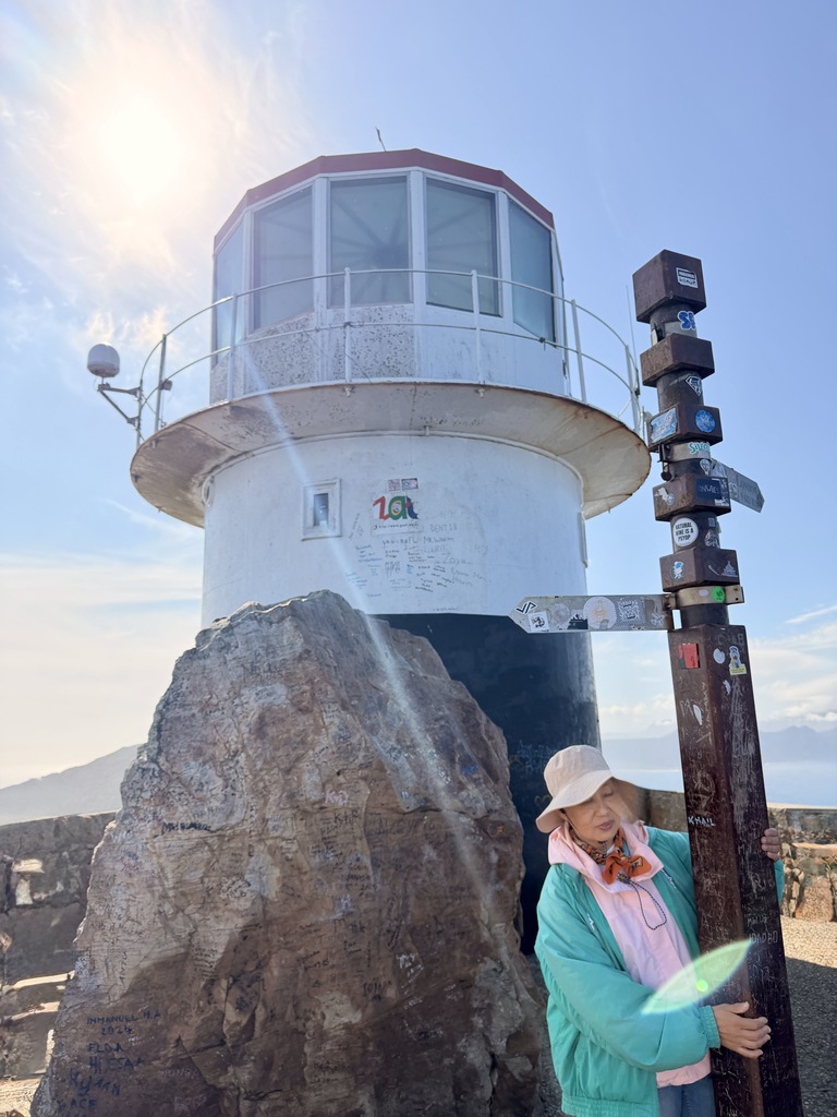 Cape of Good Hope Day Trip – Family Fun in South Africa 19 Lighthouse with scenic background and signpost.