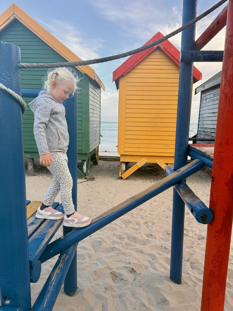 A young girl walking on a wooden playground.