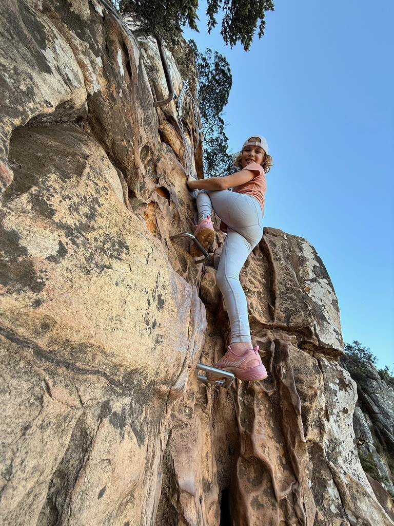 Child climbing a rocky surface outdoors.
