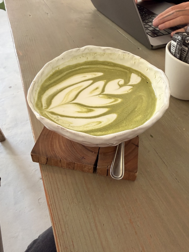 Big cup of green matcha latte on a wooden table.