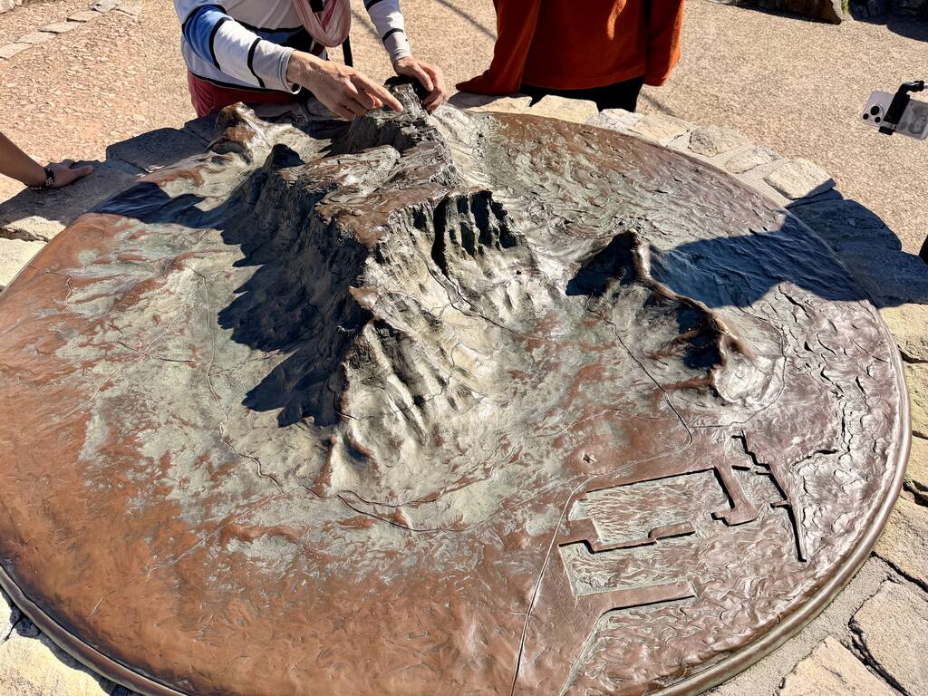 Bronze 3D relief map of Table Mountain at the summit, showing detailed mountain ridges with visitors touching the model.