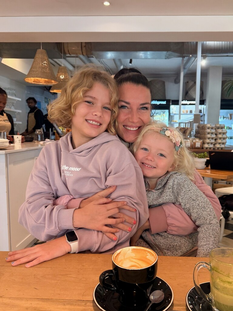 Living in Cape Town with Kids – What It’s Really Like 15 A mum and her two daughters cuddling in a cafe.