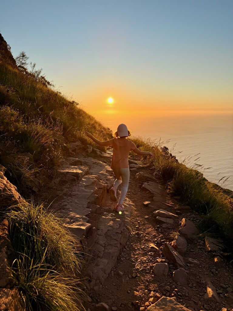 Lion's Head Hike with Kids – Is It Safe? Honest Family Guide 7 Child hiking at sunset near ocean.