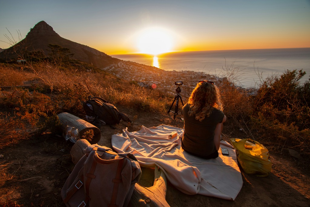 Woman on a picnic blanket enjoying the sunset on a hill.