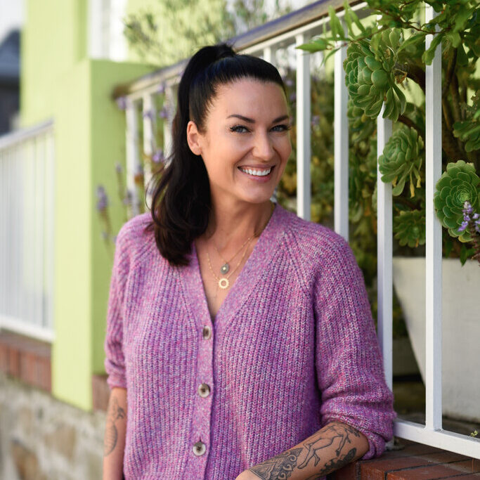 Woman posing in front of a wall.