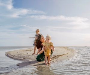 Mum with two young daughters on the beach.